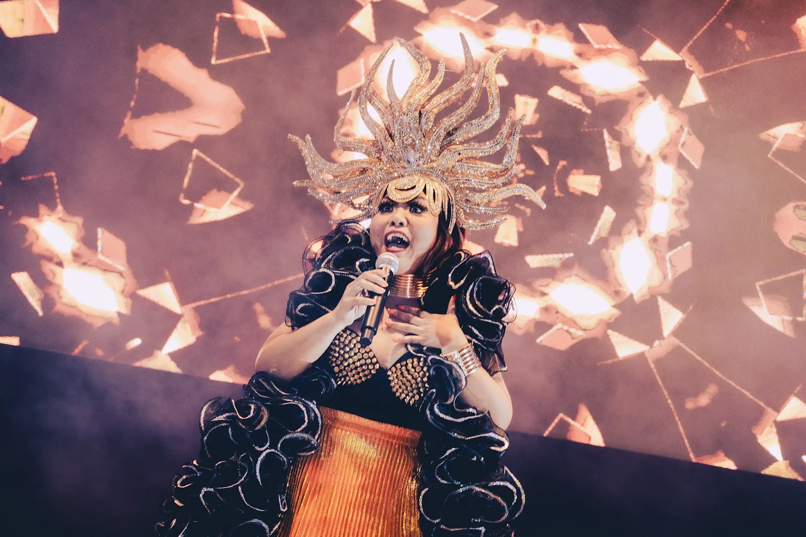 A performer singing in an elaborate gold headdress