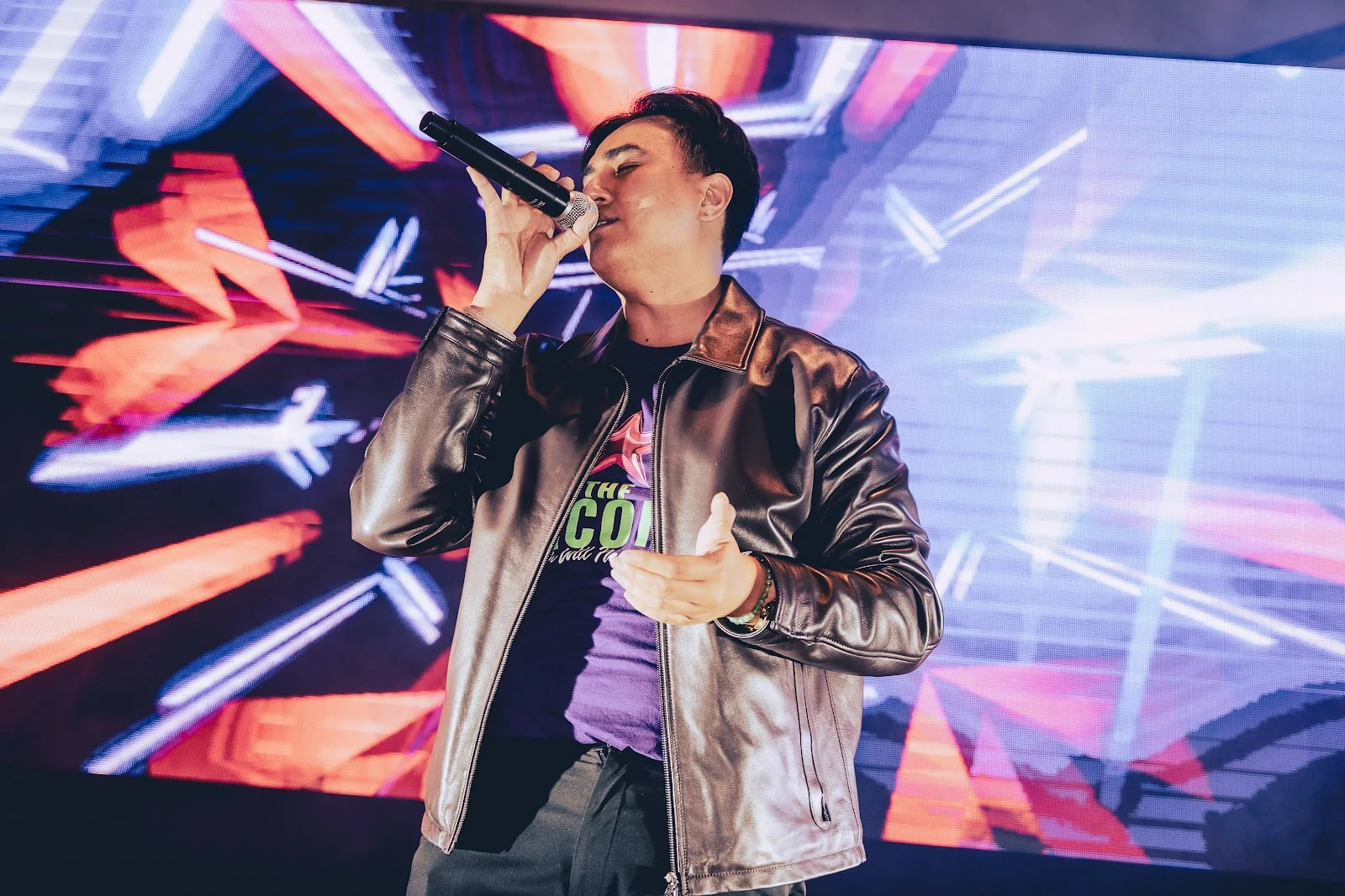 A singer performing in front of THE ICON stage screen